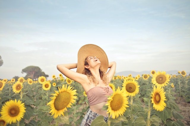 Happy woman in a field of sunflowers after finding ways to heal the body after substance abuse